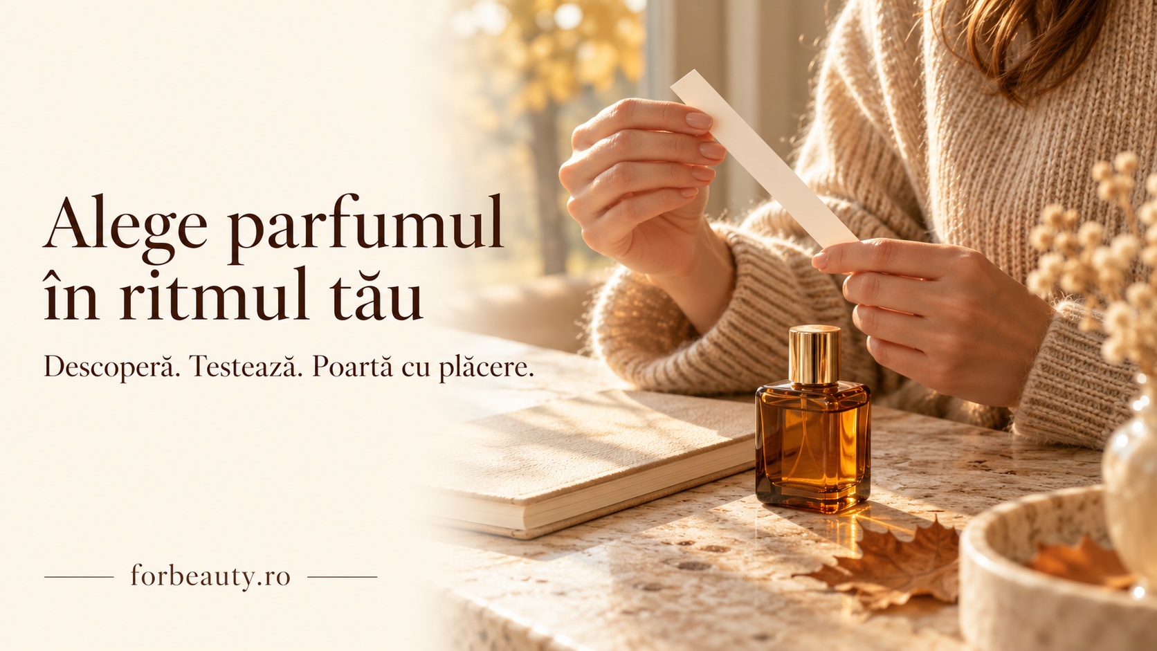 O femeie ține o bandă de testare a parfumului lângă un flacon ambrat, într-un decor luminos de toamnă.